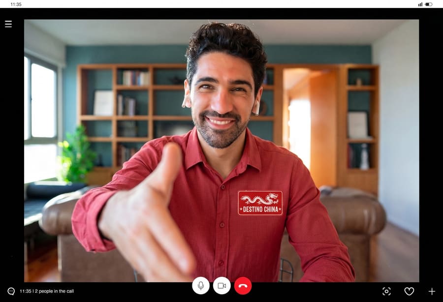 un asesor de viajes dando la mano para saludar cordialmente viste una playera roja con un logo de dragon