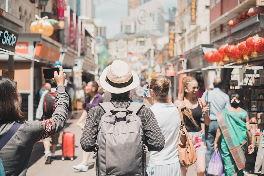 viajero, caminando por las calles de china, vestido con camisa gris y sombrero blanco con una mochila es su espalda